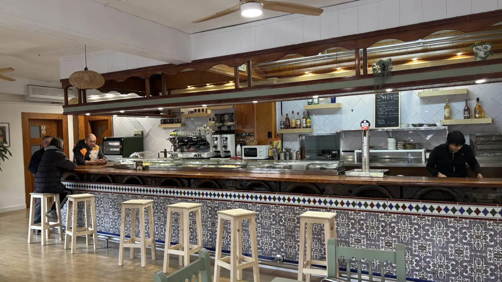 La barra de El Olivo por dentro, con taburetes de madera y el frente de azulejo