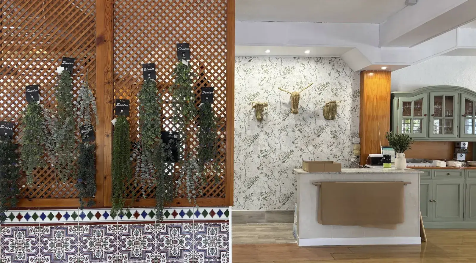 Un rincón de la sala con celosía de madera, plantas colgantes y papel pintado de hojas